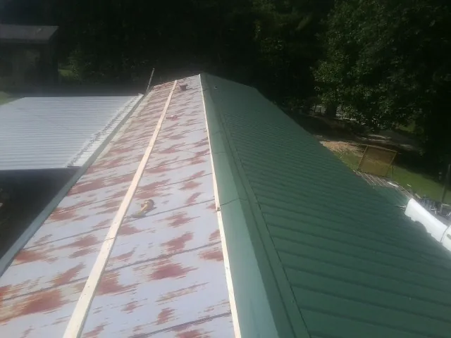 Old rusted panels beside newly installed green metal roofing — Wind Damage Roof Repair by Roofing Brothers in Ripley