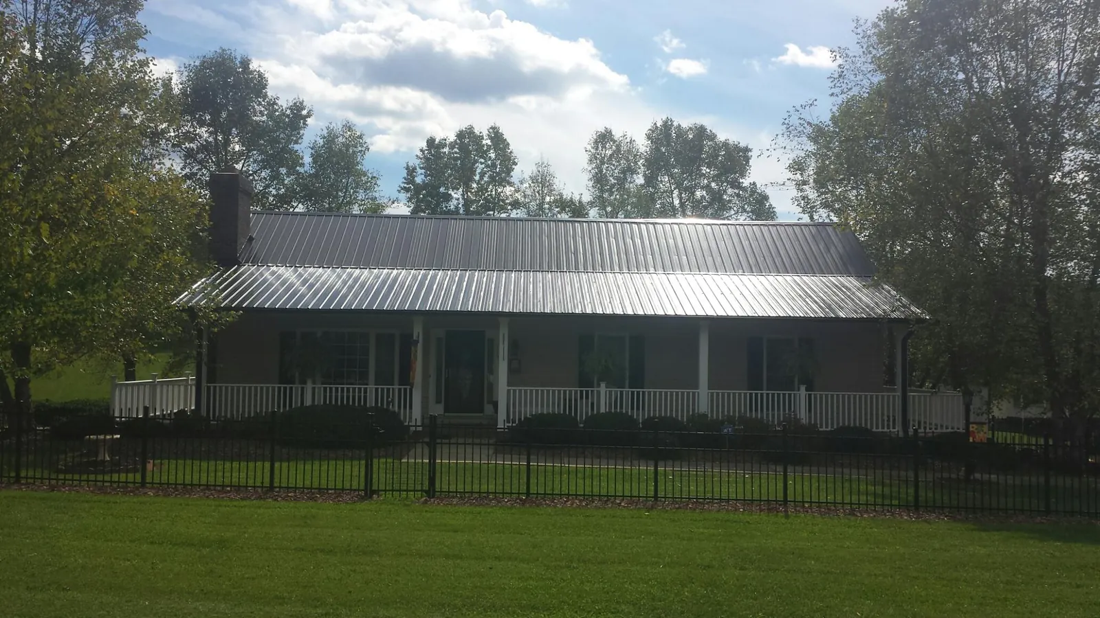 Gray metal roof on a brick ranch with a full width front porch — Gutter Guard Installation work by our crew in Ripley