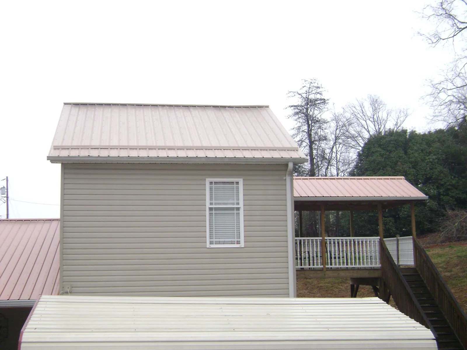 Tan metal roofs on a two story addition and attached porch, from a Roof Replacement job in Ripley